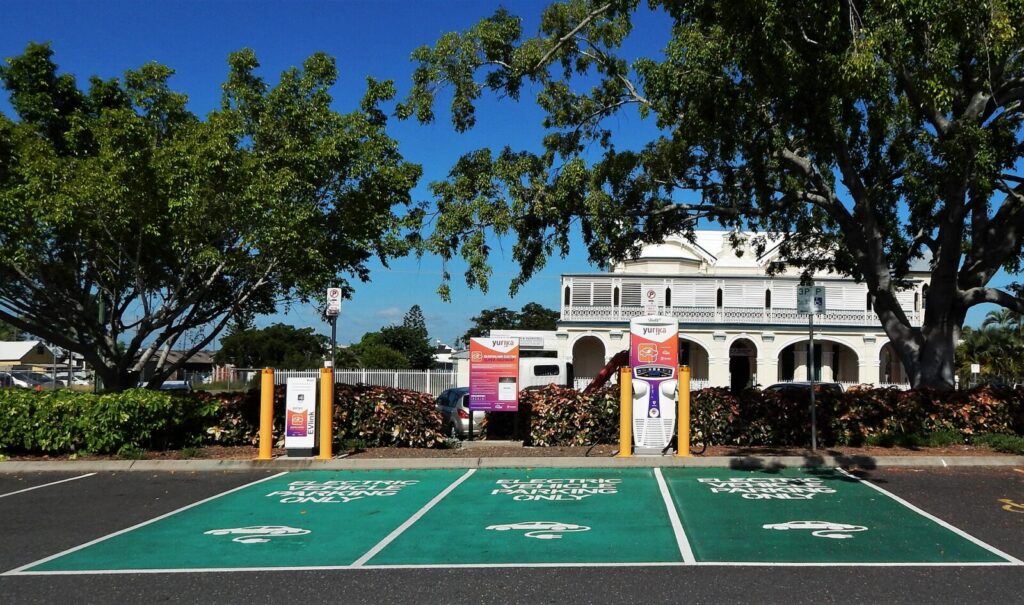 Un vehículo eléctrico conectado a una estación de carga en una ciudad colombiana