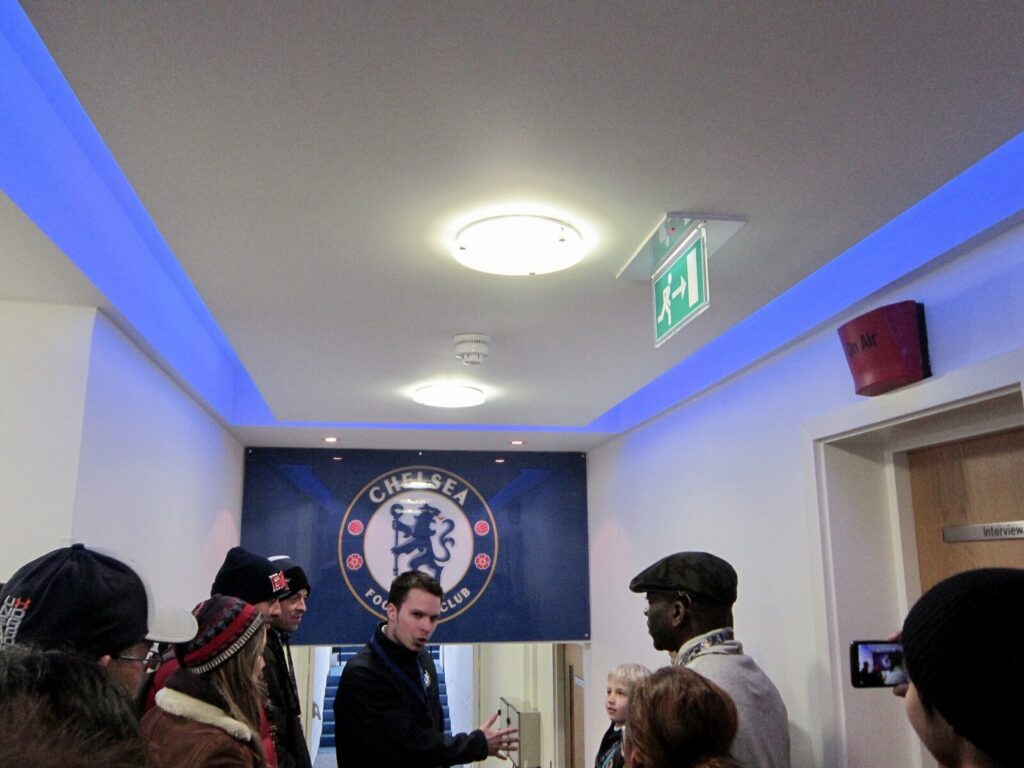 Estadio del Chelsea con los colores del club y aficionados celebrando durante un partido de fútbol