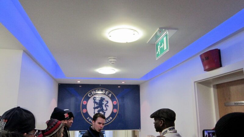 Estadio del Chelsea con los colores del club y aficionados celebrando durante un partido de fútbol