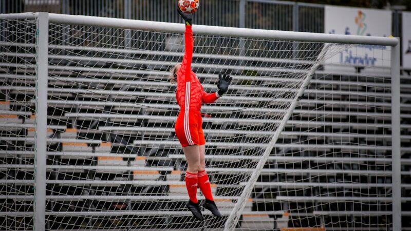 Un arquero de fútbol estirado para detener el balón durante un partido en el estadio