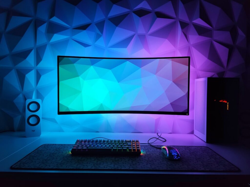 Computador de escritorio para juegos con teclado retroiluminado y monitor encendido, en un escritorio de casa