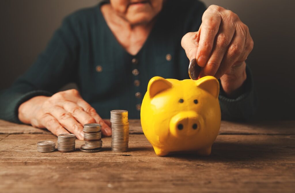 Persona organizando billetes y documentos mientras calcula sus aportes para la pensión, en una escena de planificación financiera