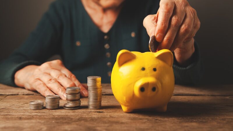 Persona organizando billetes y documentos mientras calcula sus aportes para la pensión, en una escena de planificación financiera