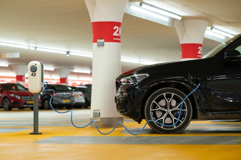 Coche eléctrico conectado a un punto de carga en un estacionamiento urbano colombiano