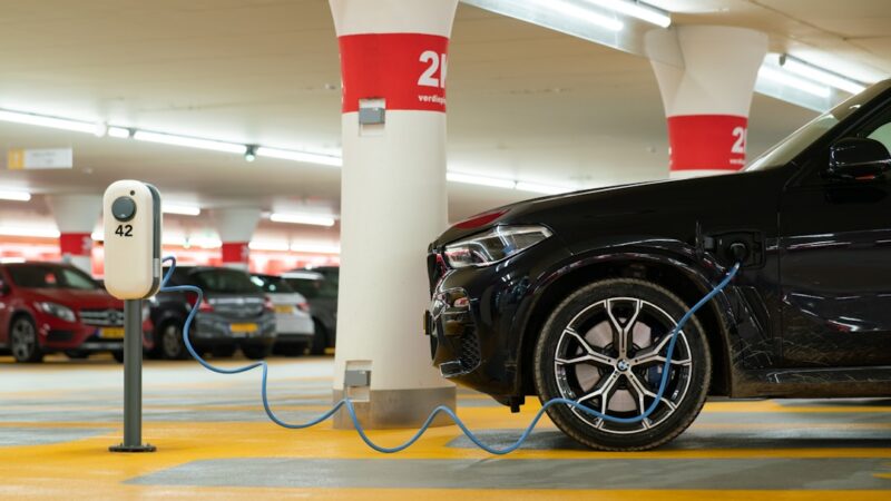 Coche eléctrico conectado a un punto de carga en un estacionamiento urbano colombiano
