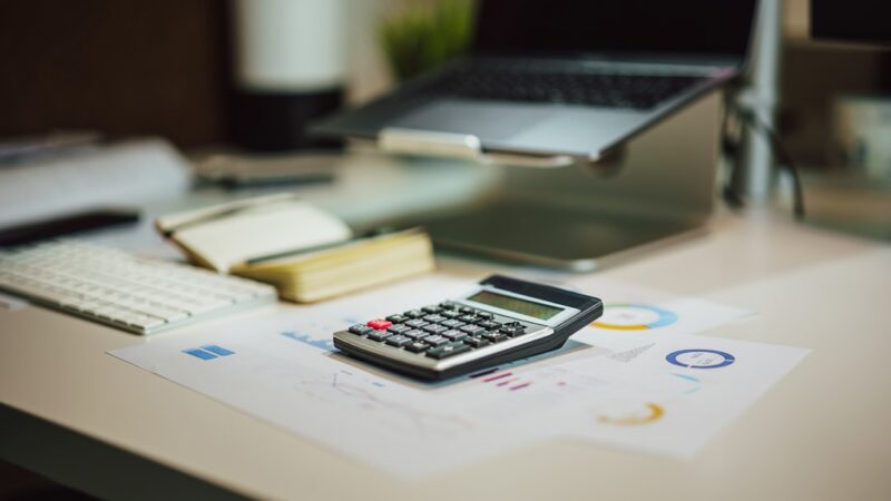 Papeles con formularios tributarios y una calculadora sobre un escritorio