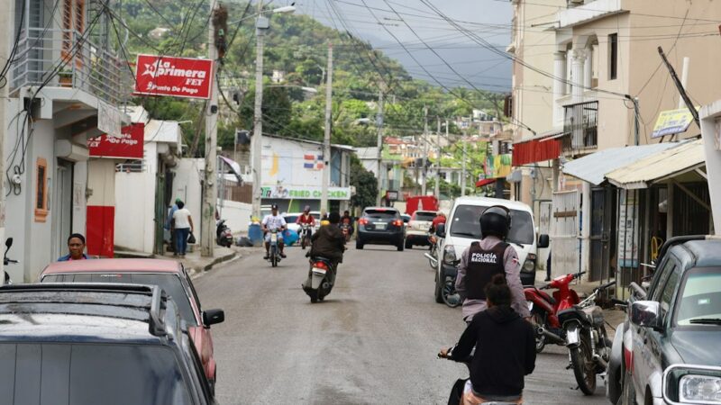 Funcionario de tránsito revisando documentos junto a un vehículo en una vía urbana