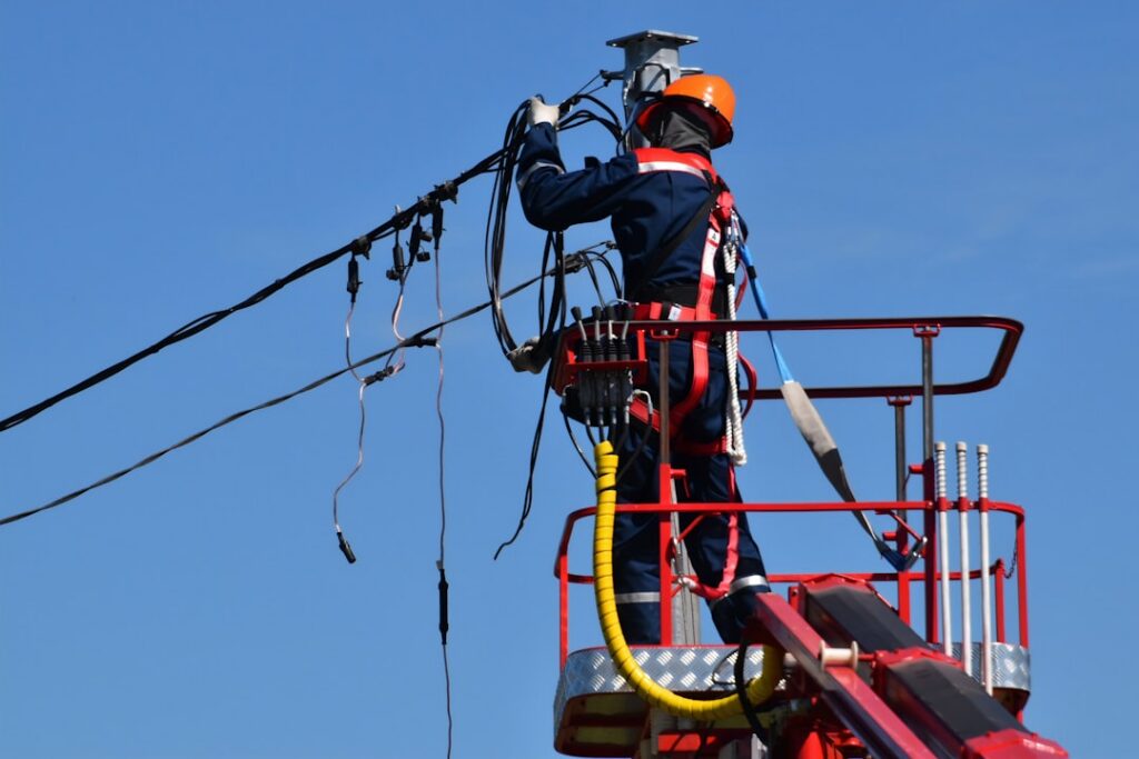 Trabajador realizando labores de mantenimiento en un poste de energía eléctrica, imagen de referencia