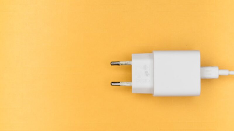 Teléfono inteligente con cable de carga conectado y pantalla encendida durante la noche