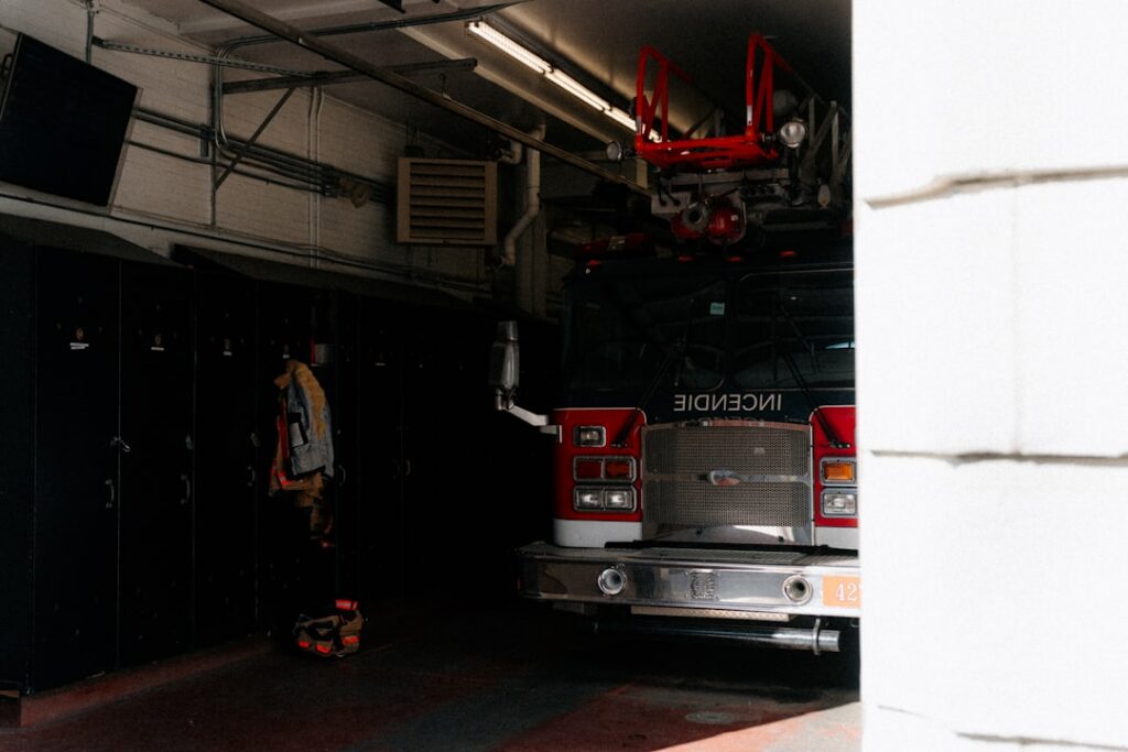 Vehículo de bomberos rojo estacionado frente a una estación de emergencias