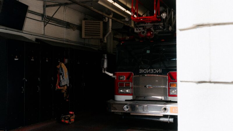 Vehículo de bomberos rojo estacionado frente a una estación de emergencias