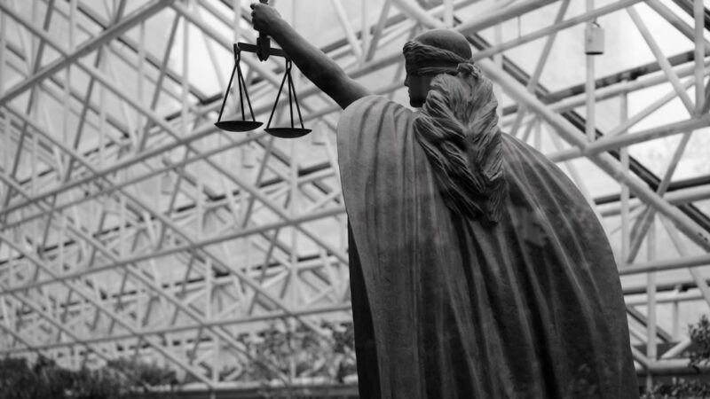 Balanzas de la justicia junto a libros de derecho, en alusión a la orden de captura por el feminicidio de Claudia Tacoronte en México