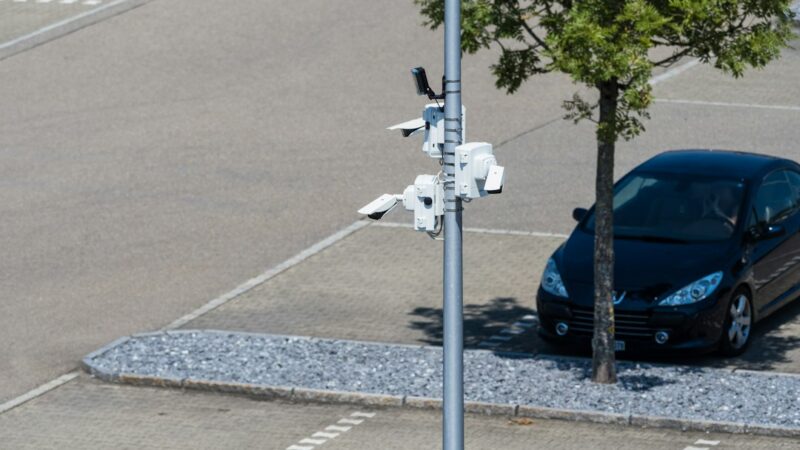Vehículo particular estacionado junto al andén en un sector urbano, con cámaras de seguridad en el entorno