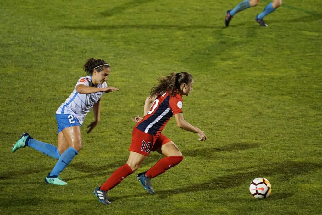 Jugadoras de fútbol disputan un partido femenino ante las tribunas de un estadio
