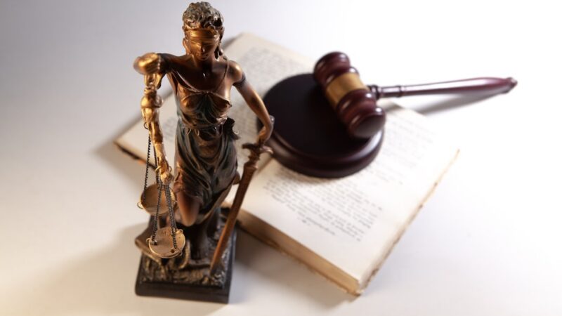 Balanzas de la justicia y un mazo de juez, símbolos del derecho que ilustran la ley de sometimiento