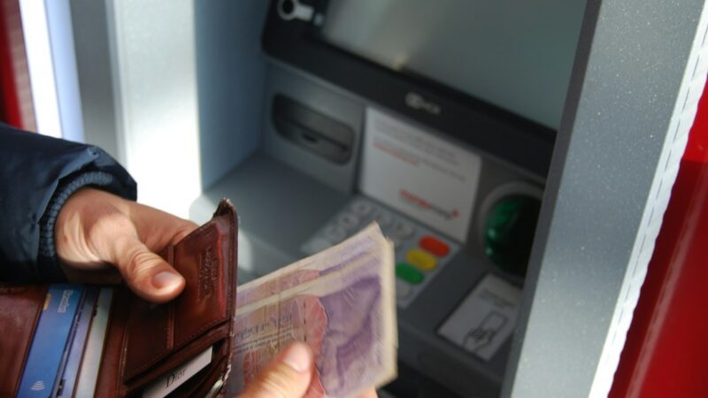 Persona recibiendo billetes en el mostrador de una tienda