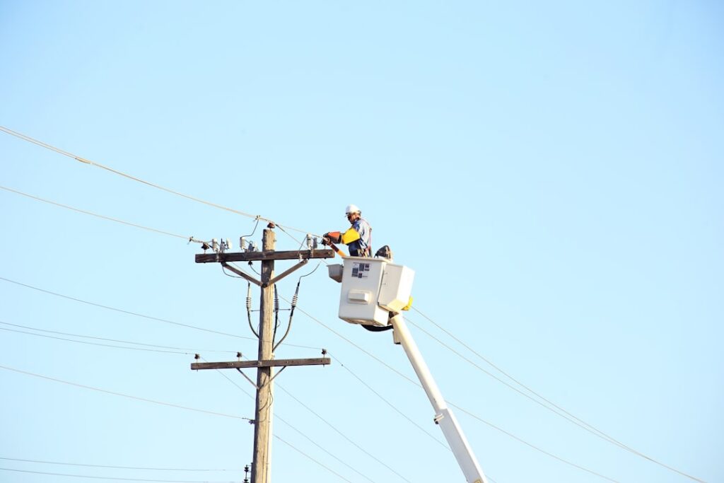 Trabajadores de servicio eléctrico laborando en líneas de distribución de energía en una zona urbana