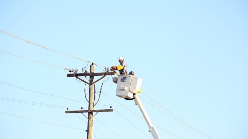 Trabajadores de servicio eléctrico laborando en líneas de distribución de energía en una zona urbana