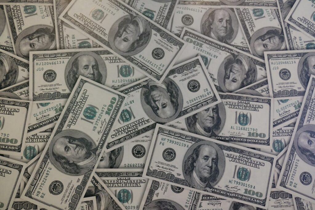 Billetes de dólar y monedas sobre una superficie, en referencia al alza de la tasa de cambio en Colombia