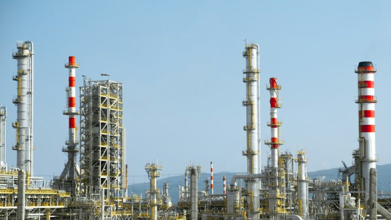 Instalación de la industria petrolera con tanques y estructuras de producción, imagen de referencia de la variación en el precio del crudo.