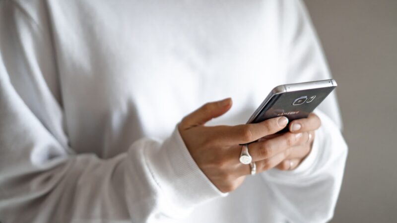 Persona sostiene un celular y activa el control de voz de una aplicación
