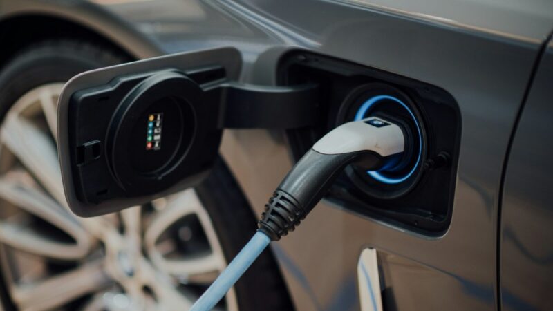 Un carro eléctrico conectado a un punto de carga con su cable de recarga