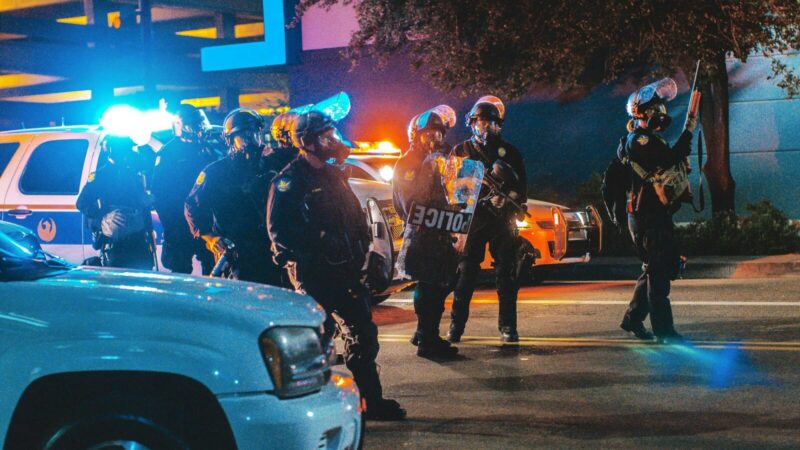 Agente de policía custodia a un detenido con esposas durante un operativo de traslado