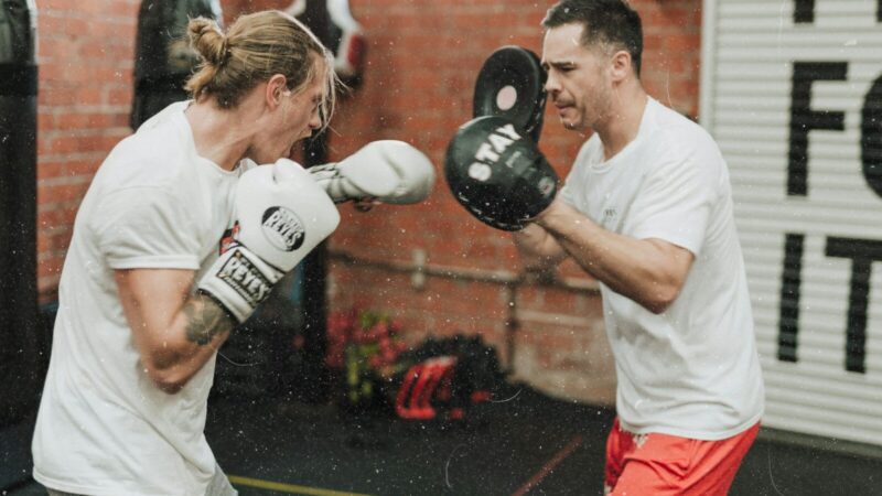Guantes de boxeo y equipamiento de entrenamiento en un gimnasio, escenario de la colaboración que une deporte y videojuegos.
