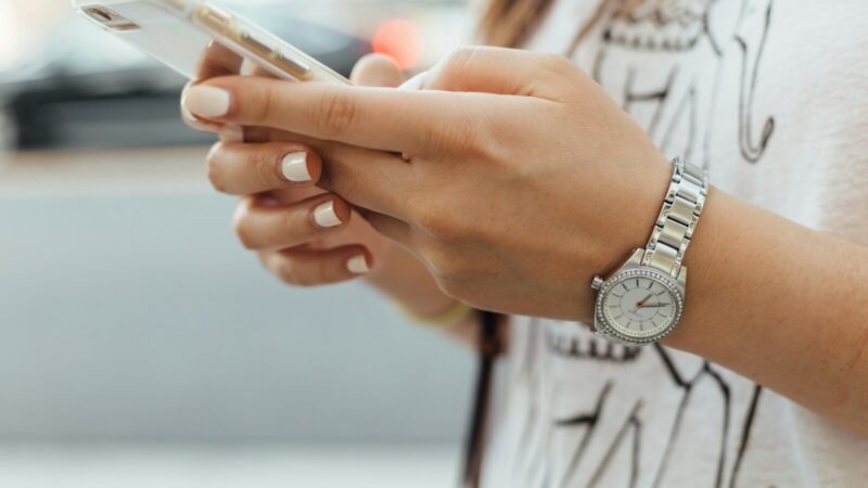 Mujer revisando y respondiendo mensajes en una red social desde un teléfono celular