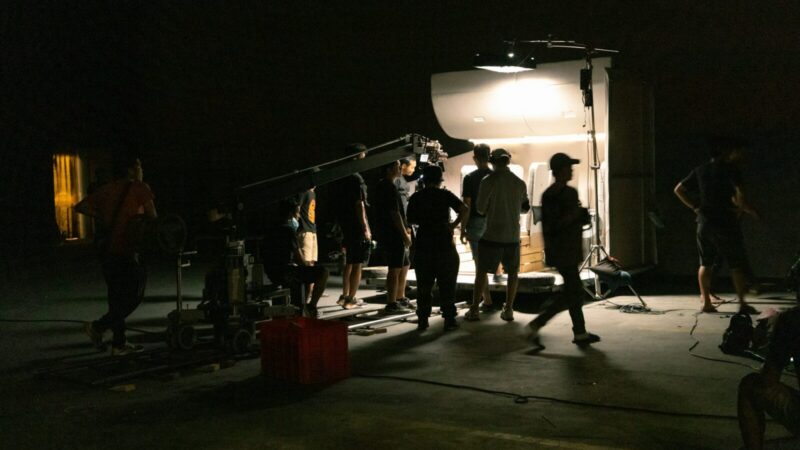 Set de filmación con equipo de producción y cámara de cine durante el rodaje de una obra audiovisual