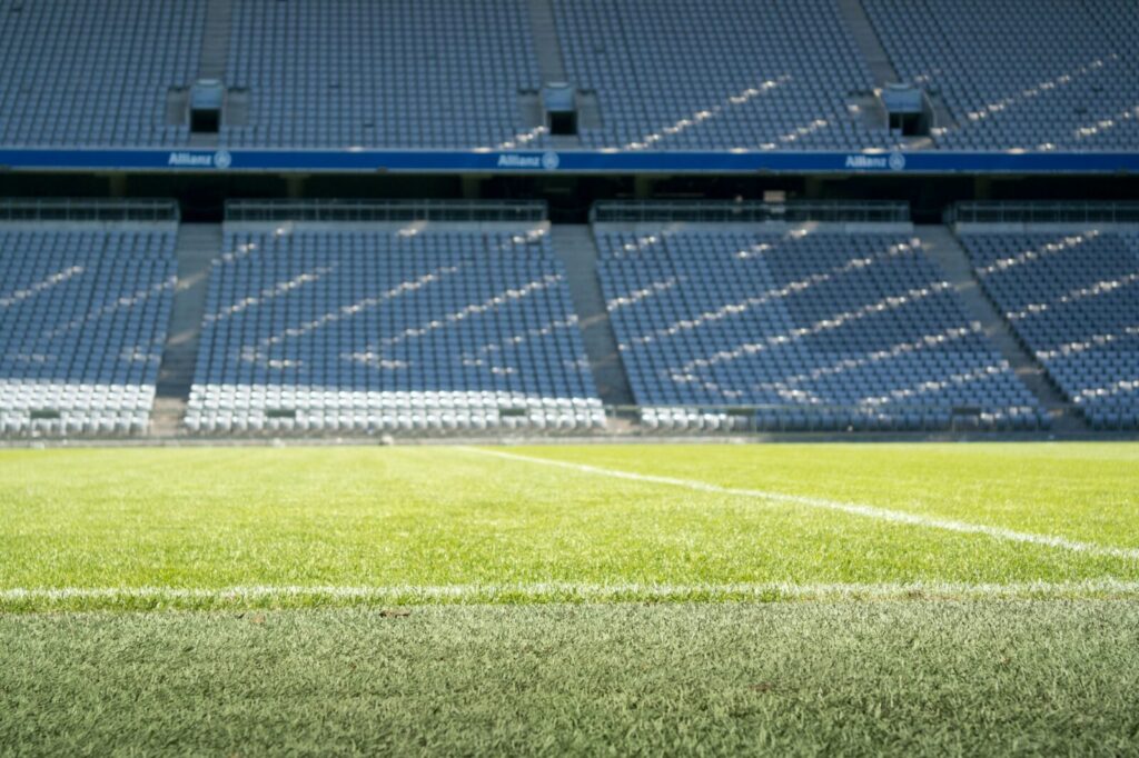 Director técnico observa un partido de fútbol desde la zona de banquillos de un estadio