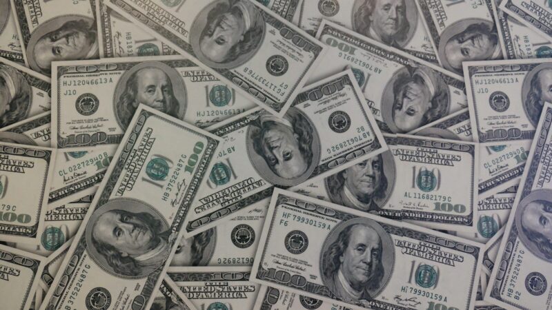 Billetes de dólar junto a monedas que representan el comportamiento del mercado cambiario