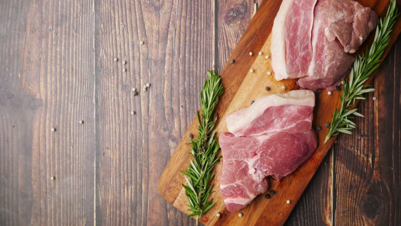 Productos cárnicos preparados para exportación junto a contenedores en un puerto comercial