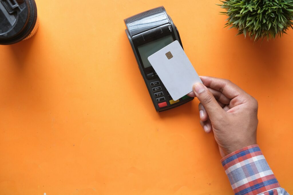 Cliente acerca una tarjeta a un celular para realizar un pago sin contacto en un comercio