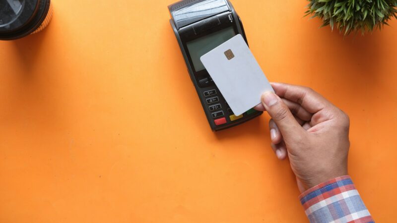 Cliente acerca una tarjeta a un celular para realizar un pago sin contacto en un comercio