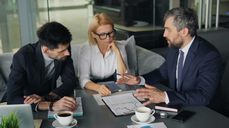 Documentos y personas reunidas en una mesa de trabajo sobre economía y competitividad