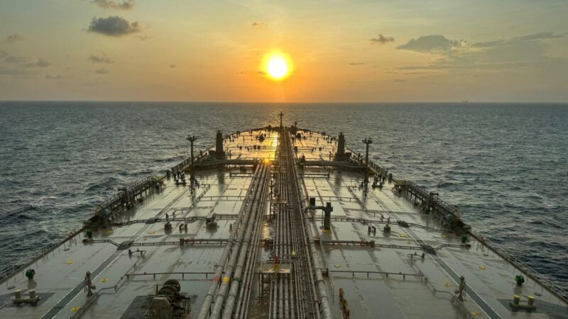 Barriles de petróleo y un buque cisterna en una escena relacionada con el mercado energético