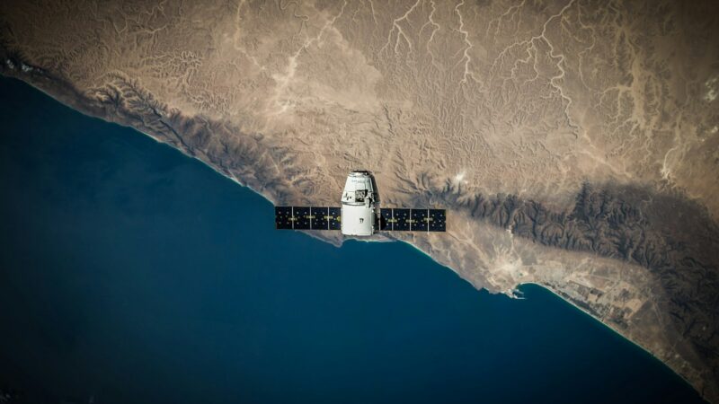 Representación de un satélite observando contaminantes y humo sobre la atmósfera terrestre