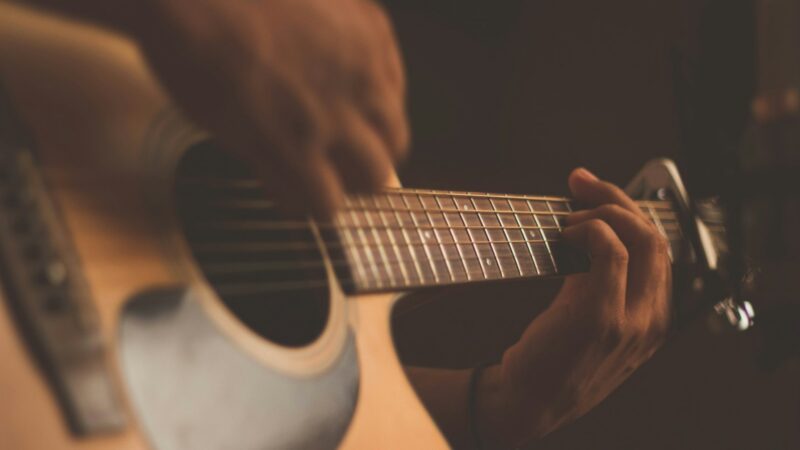 Cantautor con guitarra durante una presentación musical de carácter cultural