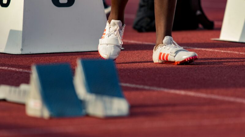 Atletas compiten en una carrera de relevos sobre una pista de atletismo