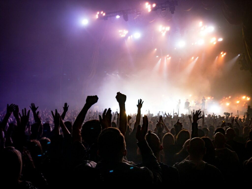 Asistentes disfrutando un festival de música electrónica con luces y escenarios iluminados de noche