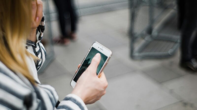 Persona sosteniendo un teléfono inteligente, símbolo del riesgo de programas espía que acceden a la cámara móvil