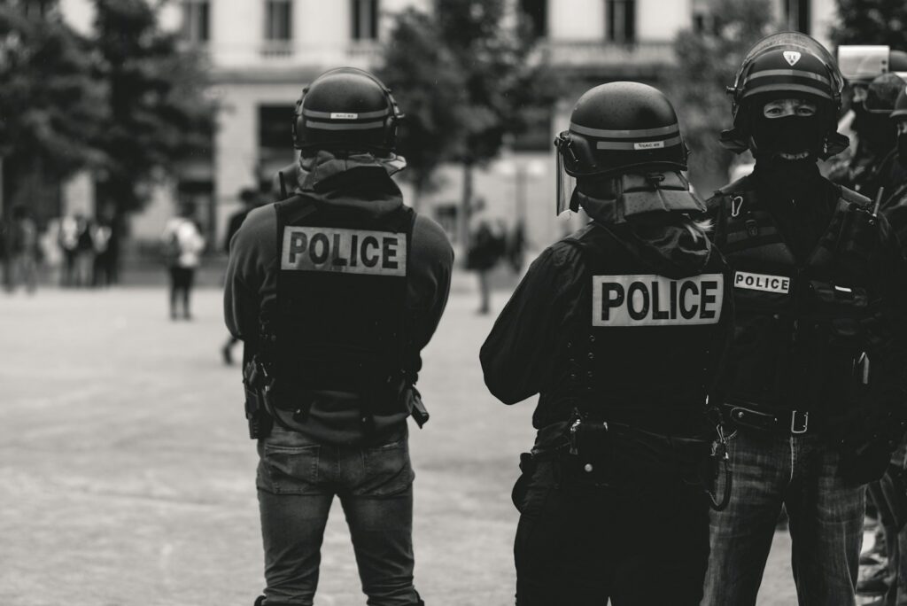 Personas participan en una manifestación mientras agentes de la Policía vigilan la jornada