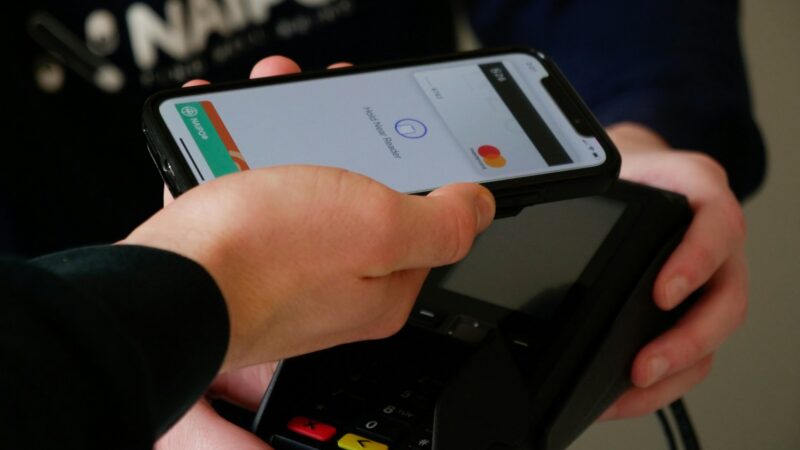 Persona realizando un pago con código QR desde un celular en un comercio