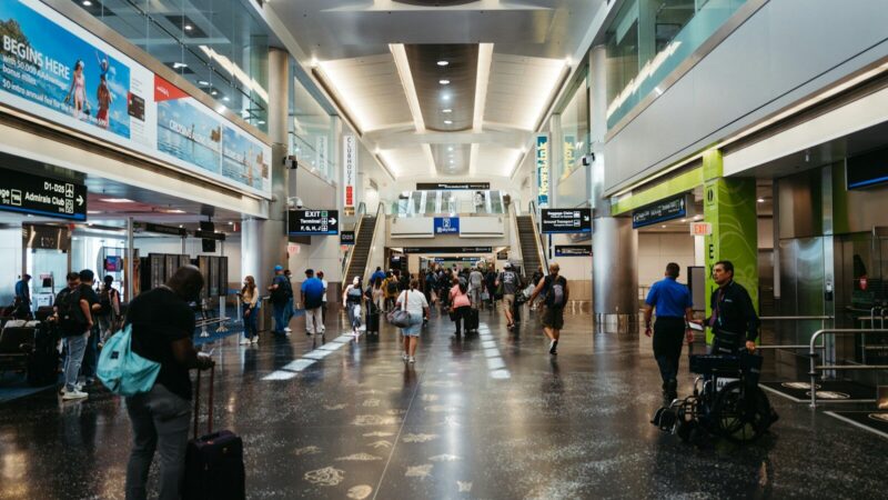 Pasajeros en una terminal aeroportuaria junto a paneles de información sobre sus vuelos.