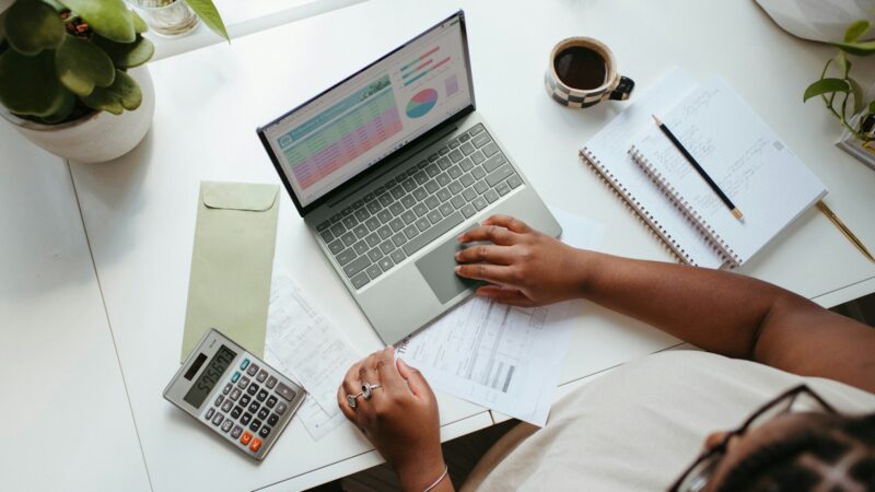 Persona revisando documentos y calculando gastos del hogar junto a una calculadora