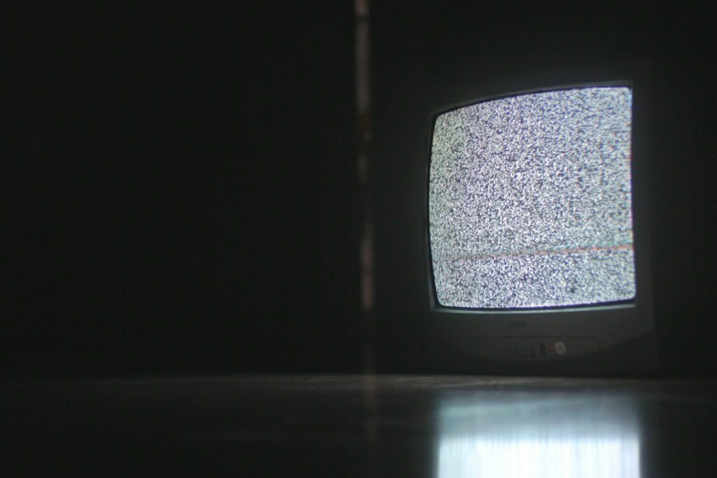 Televisión encendida en un ambiente oscuro, en ilustración alusiva a los estrenos de terror de la plataforma en octubre