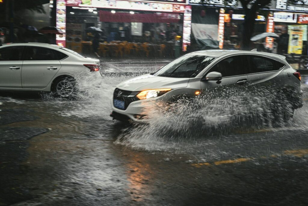 Automóviles avanzan lentamente por una calzada cubierta por agua acumulada.