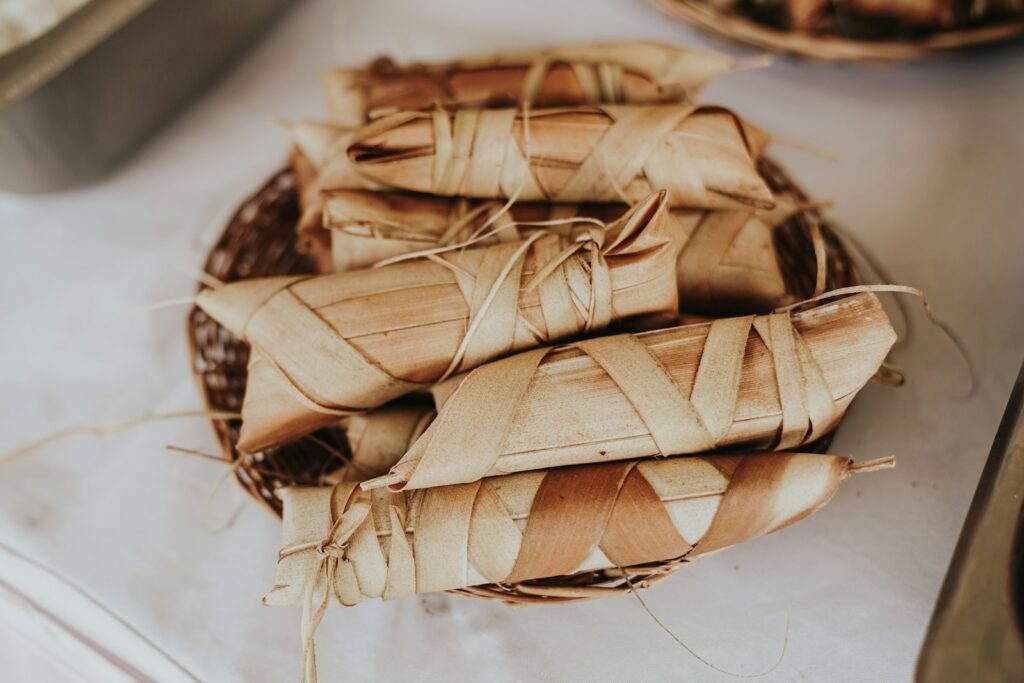 Tamales envueltos en hojas y dispuestos sobre una mesa.