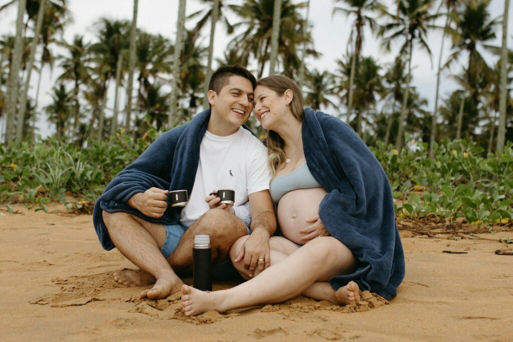 Pareja anunciando un embarazo junto a una ecografía en una playa